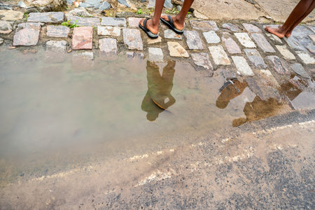 Reflection of unidentified people in a puddle. Rainwater, rainy day. Brazilの写真素材
