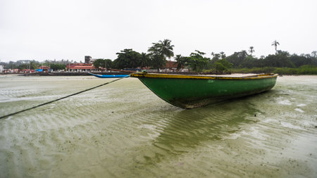 Fishing boat anchored on the sand of a dry beach. Quite rainy day with dense clouds. Means of transport.の写真素材