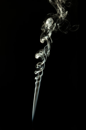 Blue-white smoke coming from the tip of an incense stick. Studio shot.の写真素材