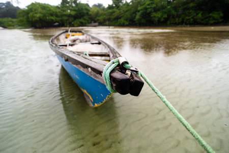 Fishing boat anchored on the sand of a dry beach. Quite rainy day with dense clouds.の写真素材