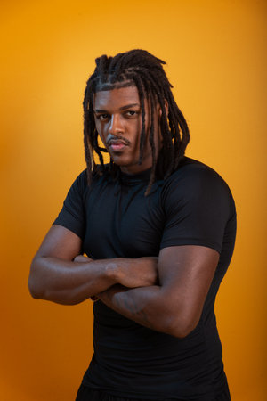 Studio portrait of handsome young man wearing black outfit and posing for photo against orange colored background. Confident and calm person.の写真素材