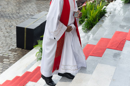 Priest dressed in character walking up a staircase with a red carpet. Catholic religion.の写真素材