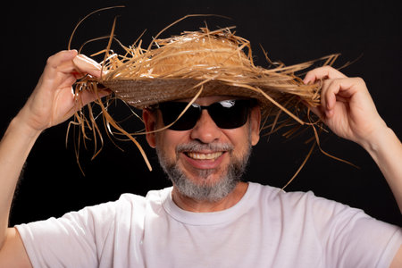 Smiling bearded man wearing straw hat and white shirt dressed up for Sao Joao party in Brazil.の写真素材