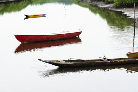 A mighty river with anchored fishing and transport boats and canoes. Rainy and cold day.