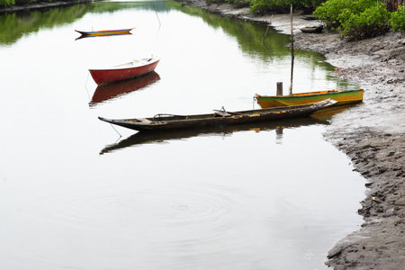 A mighty river with anchored fishing and transport boats and canoes. Rainy and cold day.