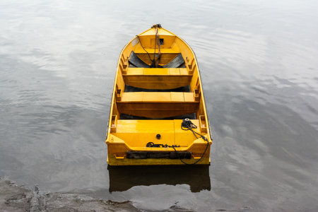 A yellow fishing boat stopped on the river on a rainy day. Lifestyle.の写真素材