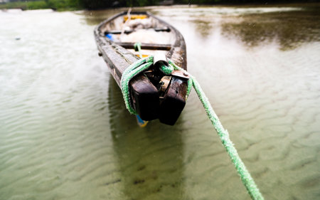 Fishing boat anchored on the sand of a dry beach. Quite rainy day with dense clouds. Means of transport.の写真素材
