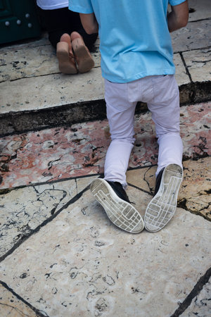 Body part view of people kneeling praying at the door of a church. Legs feet and shoesの写真素材