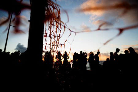 Unidentified people silhouetted through red ribbon fence against dramatic sunset. People on vacation. Travel.の写真素材