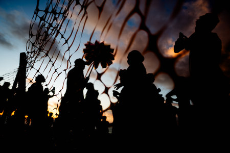 Unidentified people silhouetted through red ribbon fence against dramatic sunset. People on vacation. Travel.の写真素材
