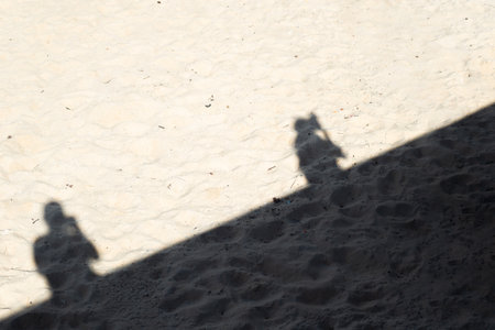 Shadows of two people projected onto the sand of a beach. People traveling. Lifestyle.