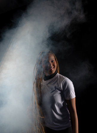Portrait of a beautiful young woman with braided hair wearing a white outfit and posing for a studio...