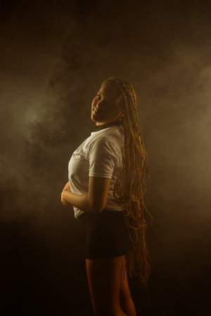 Portrait of a beautiful young woman with braided hair wearing a white outfit and posing for a studio...