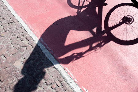 Shadow of a bicycle projected onto a cycle path. Person exercising. Cyclist in action. Lifestyle, sports practice.の写真素材
