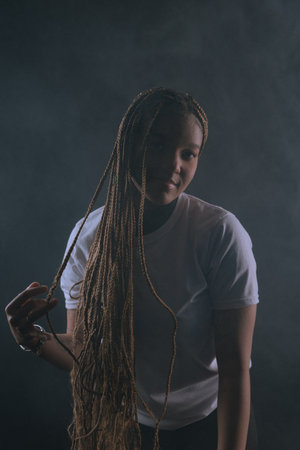 Salvador, Bahia, Brazil - August 30, 2025: Beautiful woman with braids posing for a studio photo isolated on a smoky background. Salvador, Brazil.の写真素材