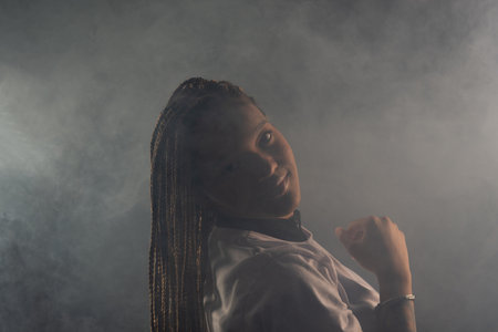 Salvador, Bahia, Brazil - August 30, 2025: Beautiful woman with braids posing for a studio photo isolated on a smoky background. Salvador, Brazil.の写真素材