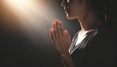 A tranquil portrait of a woman with her hands clasped in prayer, bathed in soft light. This moment conveys focus, faith, and inner peaceの素材
