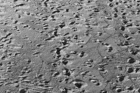 A sandy beach surface covered with countless footprints and trails. The warm evening light...