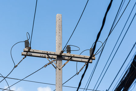 Photograph of a wooden power pole with wires connected to ceramic insulators.の写真素材