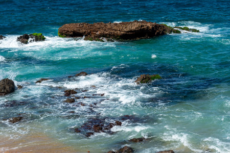 A view of the sea moving between the rocks on a beach. The image conveys a sense of peace and the...