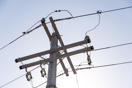 View of an electricity pylon against a blue sky. Power transmission network. Technology.