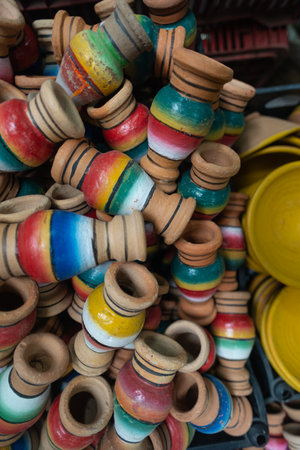 A dense stack of small wooden vases hand-painted with rainbow-colored stripes. Rustic terracotta bases and vibrant colored bands.の写真素材