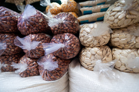 A vibrant market display showcases almonds and peanuts packed in clear plastic bags, neatly stacked for shoppers to enjoy.の写真素材