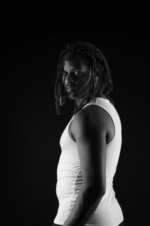 Black and white photo. Man with dreadlocks looking at the camera. Studio photoshoot.