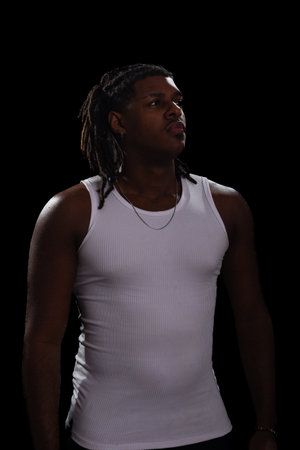 Handsome young man with dreadlocks and a white shirt looking to the side during a photo shoot....