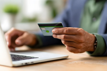 Close-up of a man's hands holding a credit card, about to finalize an online purchase on a laptop, taking advantage of Black Friday promotions. Focus on digital payment, e-commerce, and seasonal sales.の素材