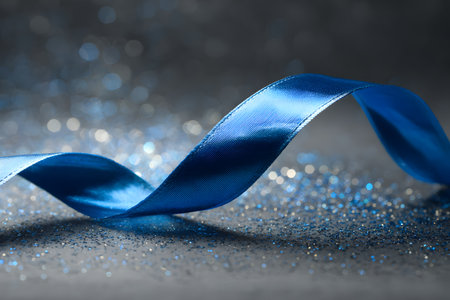 Close-up of a blue ribbon placed on a gray stone surface, representing the Blue November campaign for prostate cancer awareness and prevention.の素材