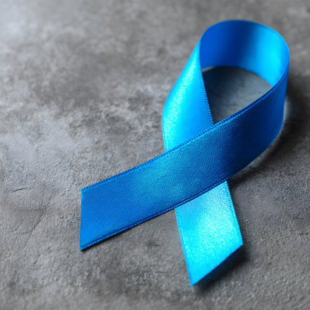 Close-up of a blue ribbon placed on a gray stone surface, representing the Blue November campaign for prostate cancer awareness and prevention.の素材