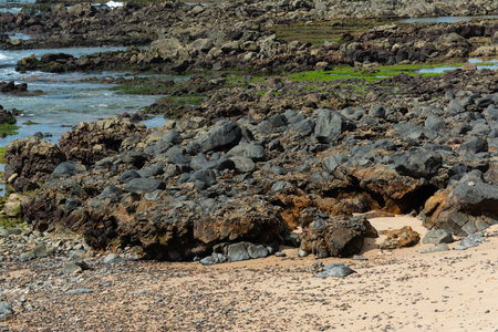 Panoramic view of a beach with rock formations and natural pools by the sea. The blue ocean...