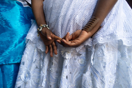 Salvador, Bahia, Brazil - November 25, 2025: Hands and Cowrie Shell Bracelet of a Bahian Woman in White Lace Dress during celebrations for Bahian Womans Day. Salvador, Bahia.のeditorial素材