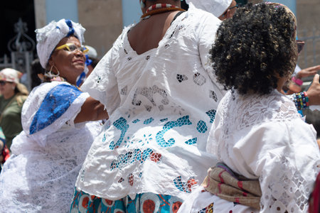 Salvador, Bahia, Brazil - November 25, 2025: A group of Bahian women in white lace clothing and colorful skirts are seen in a procession in Pelourinho, Salvador, Bahia.のeditorial素材