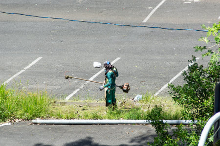 Salvador, Bahia, Brazil - November 28, 2025: A city hall employee is mowing the grass in the SÃ£o...