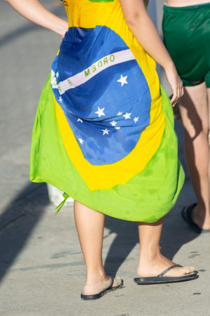Salvador, Bahia, Brazil - November 14, 2025: Rear view of a woman walking, wrapped in a sarong with the Brazilian flag design. Salvador, Bahiaのeditorial素材