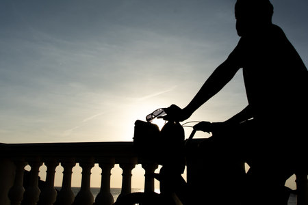 Salvador, Bahia, Brazil - December 12, 2025: Silhouette of a man on a bicycle during sunset in Barra. Salvador, Bahia.のeditorial素材