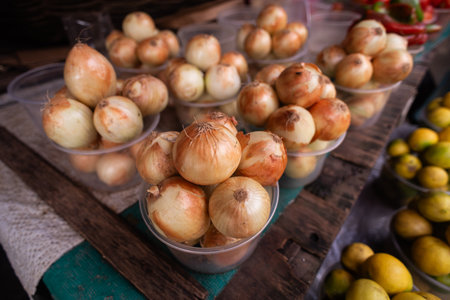 Small portions of yellow onions arranged in transparent plastic containers for sale at a popular...
