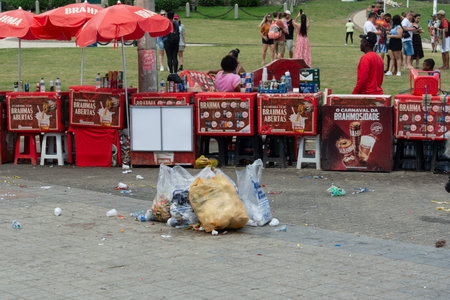 Salvador, Bahia, Brazil - February 7, 2026: Street vendors selling drinks from red coolers with bags of trash piled on the ground. Salvador, Bahia.のeditorial素材