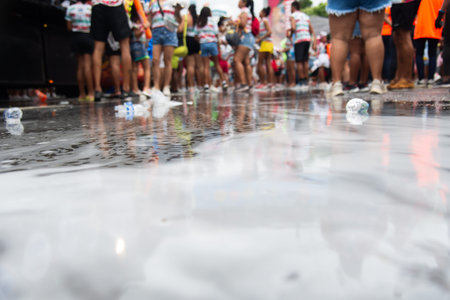 Salvador, Bahia, Brazil - February 14, 2026: Low-angle shot showing asphalt covered in foam and water with revelers in the background during the Salvador Carnival circuit in Bahia.のeditorial素材