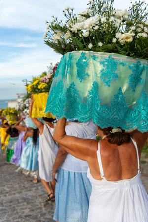 Salvador, Bahia, Brazil - February 3, 2026: Devotees lined up on a street in Itaparica carrying...