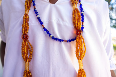 Itaparica, Bahia, Brazil - February 3, 2026: Candomble member seated displaying religious beaded necklaces over traditional white clothing at an Afro-Brazilian religious event. Amoreiras, Bahia.のeditorial素材