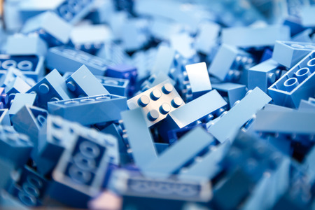 Pile of Building Blocks with focus and highlight on a selected piece with available lightの写真素材