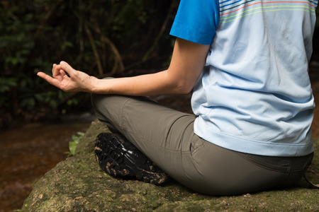 Women meditating in the woods next to a streamの写真素材