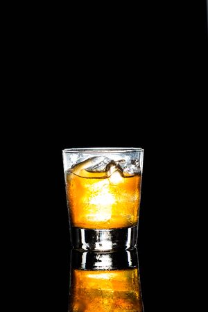 A glass of whiskey on the rocks against dark backgroundの写真素材
