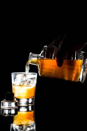 Hand pouring a glass of whiskey from a bottle in dark backgroundの写真素材