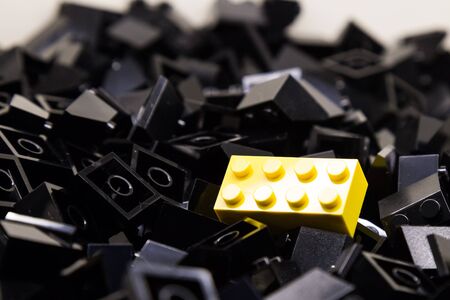 Pile of black color building blocks with selective focus and highlight on one particular yellow...