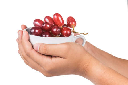 Hands holding a cup full of red grapesの写真素材