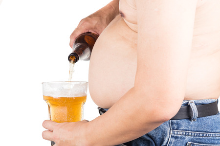 Obese man with big belly pouring a glass of refreshing beerの写真素材